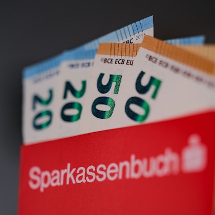 Ein Sparkassen-Sparbuch mit Geldscheinen gefüllt.