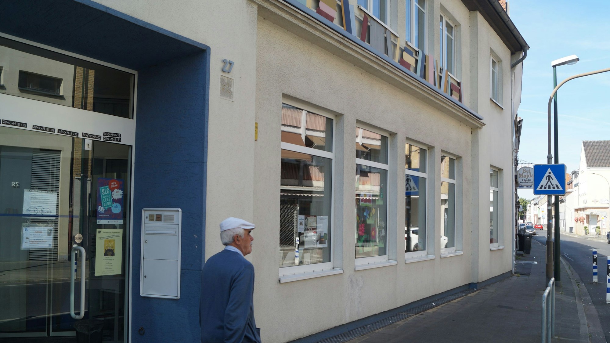 Mann vor der Fassade der Stadtbücherei Kerpen bei sonnigem Wetter
