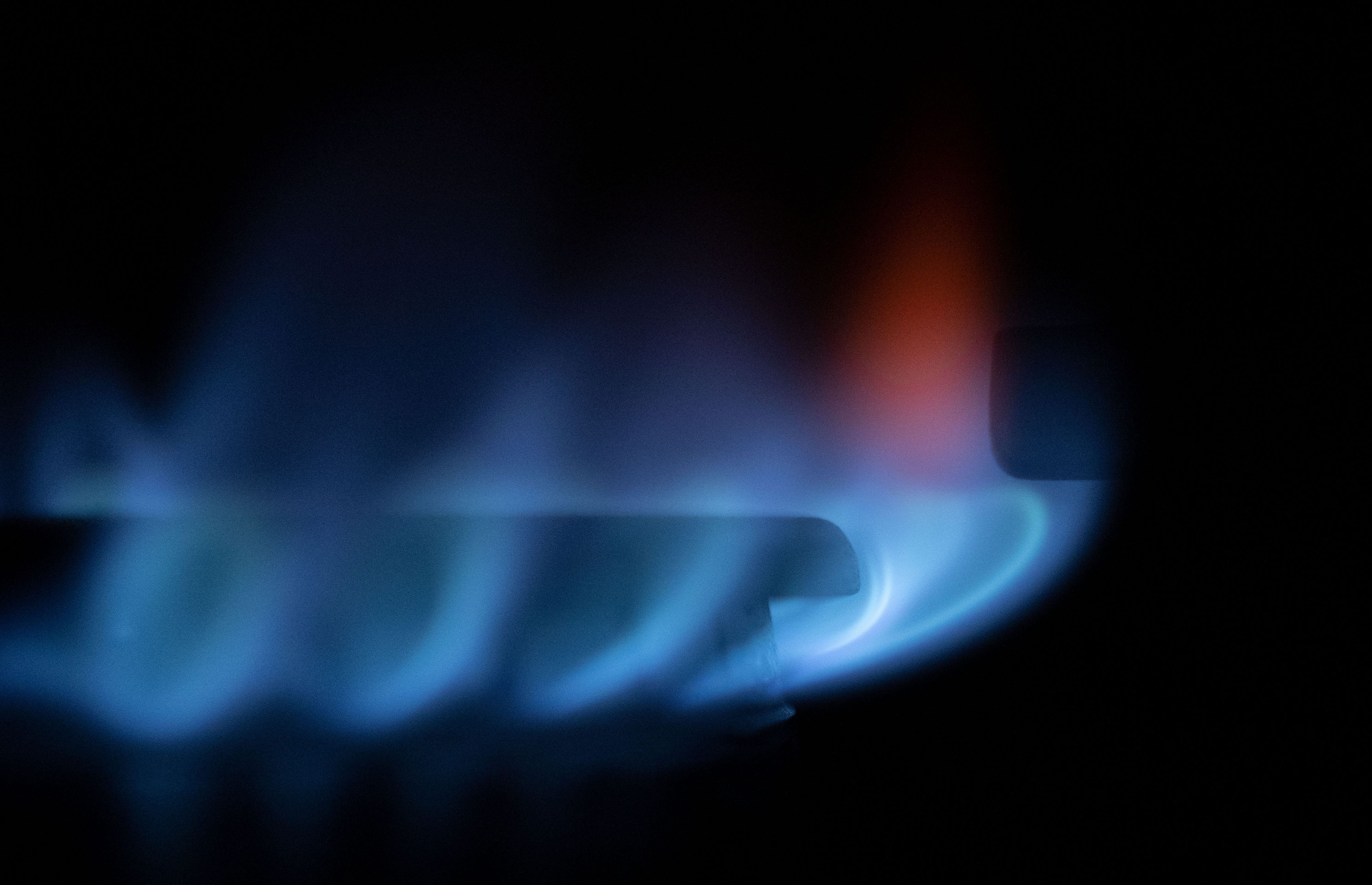 Es sind zahlreiche blau-schimmernde Gas-Flämmchen an einem Gasherd zu sehen.