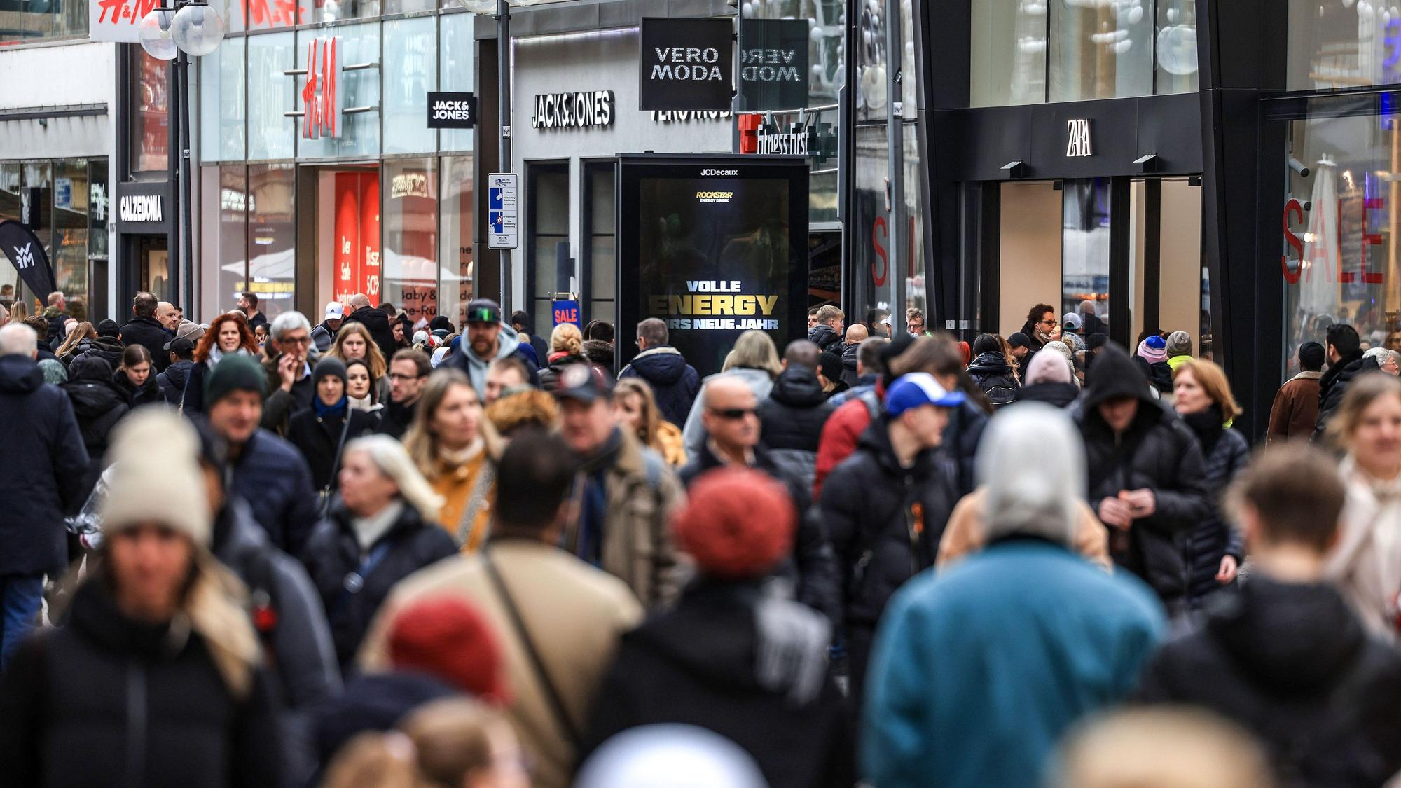 Man sieht unscharf Menschen, wie sie durch die Schildergasse laufen. Im Hintergund sind Geschäfte.