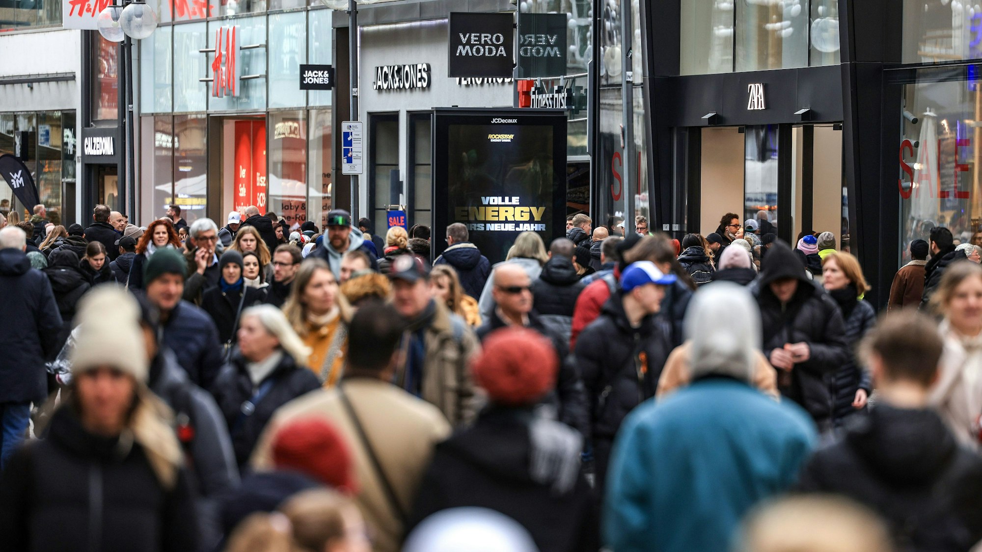 Man sieht unscharf Menschen, wie sie durch die Schildergasse laufen. Im Hintergund sind Geschäfte.