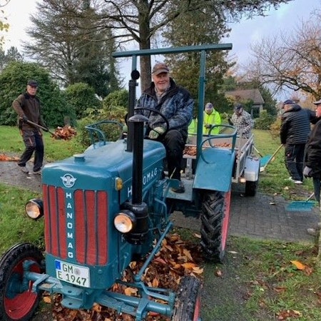 Die ehrenamtlichen Friedhofsgärtner arbeiten in Müllenbach mit einem kleinen blauen Traktor.
