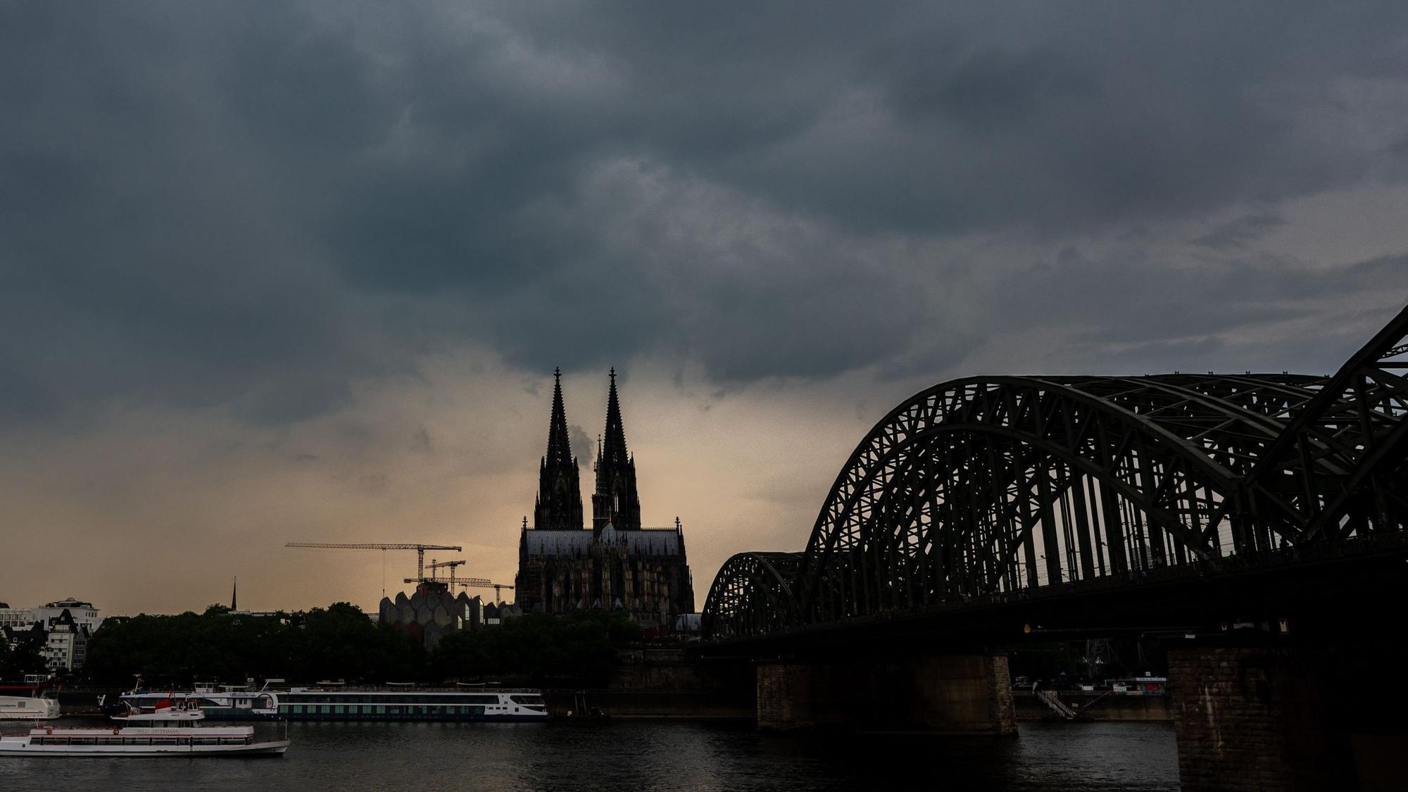 Dunkle Gewitterwolken ziehen über dem Kölner Dom auf. Im Vordergrund ist die Hohenzollernbrücke zu sehen. (Symbolbild)