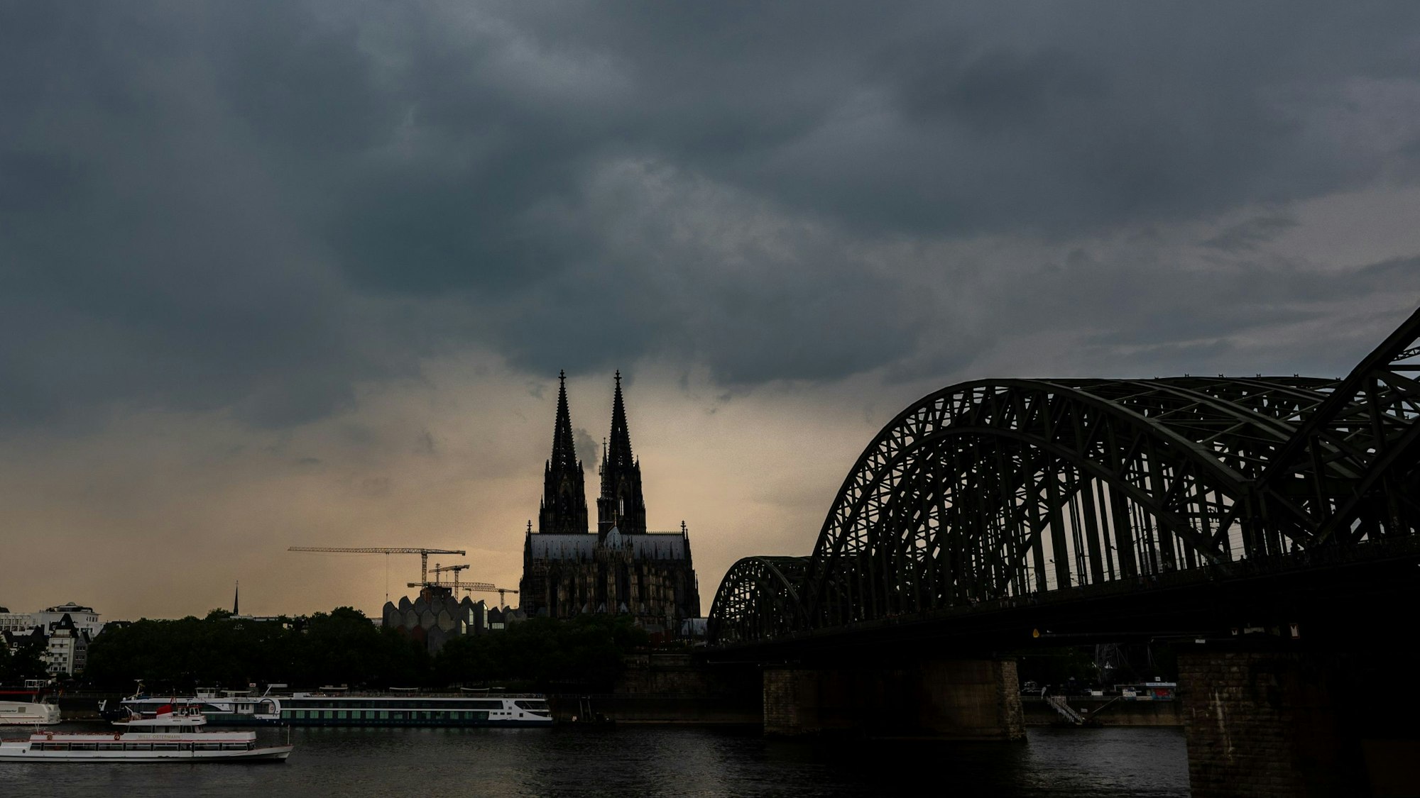 Dunkle Gewitterwolken ziehen über dem Kölner Dom auf. Im Vordergrund ist die Hohenzollernbrücke zu sehen. (Symbolbild)