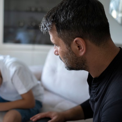 Mittelalter Mann schaut einen traurigen Jugendlichen an.