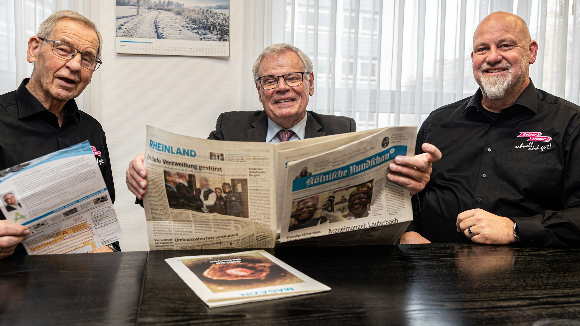 Die Männer sitzen an einem Tisch und lesen die Zeitung.