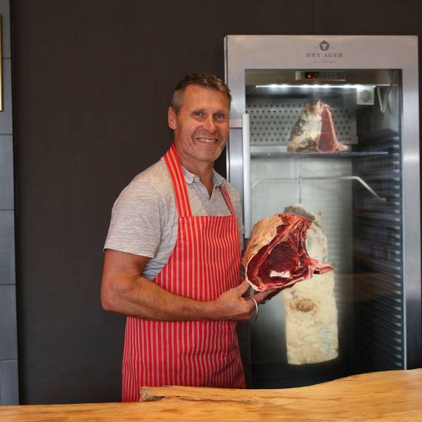 Blick auf einen Mann, der ein großes Stück Steak in den Händen hält.