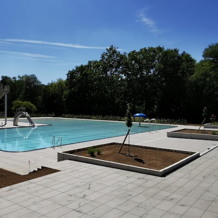 Der Außenbereich des Kombibades mit Rutsche und Beeten.