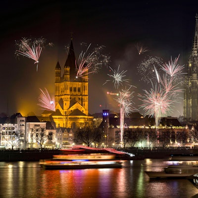 Lichtermeer am Nachthimmel von Köln. Das Silvesterfeuerwerk 2019 mit Blick auf den Dom. Im unteren Bildrand der prall gefüllte Rheinboulevard.