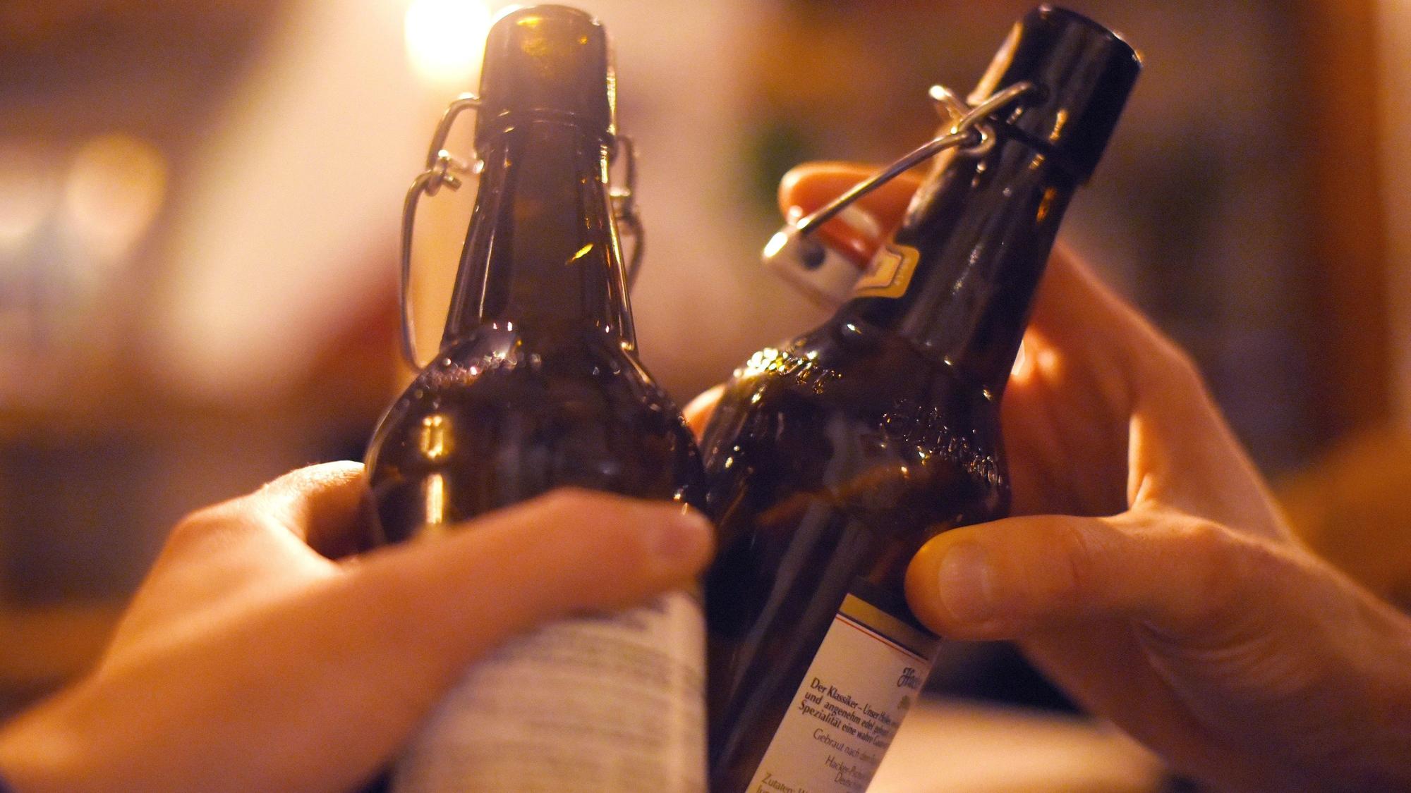 Zwei Menschen stoßen mit Bier in der Flasche an.