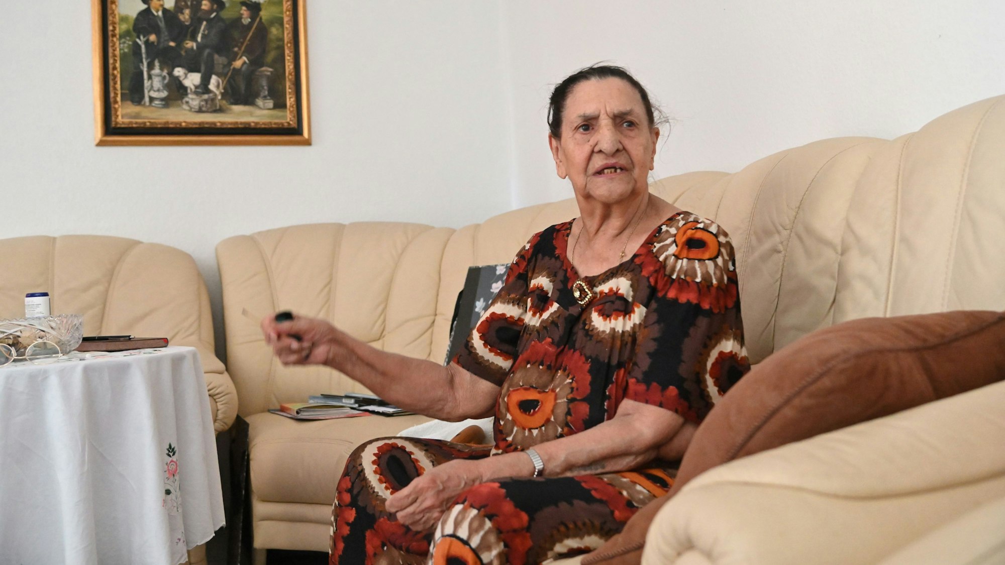 Philomena Franz sitzt auf ihrem Sofa und gestikuliert.