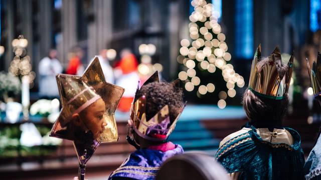 Glitzernde Gewände und ein feierlicher Augenblick: Sternsinger bei der Aussendungsfeier im Dom. In dem selbstgebastelten großen Stern eines der Kinder spiegelt sich sein Gesicht.