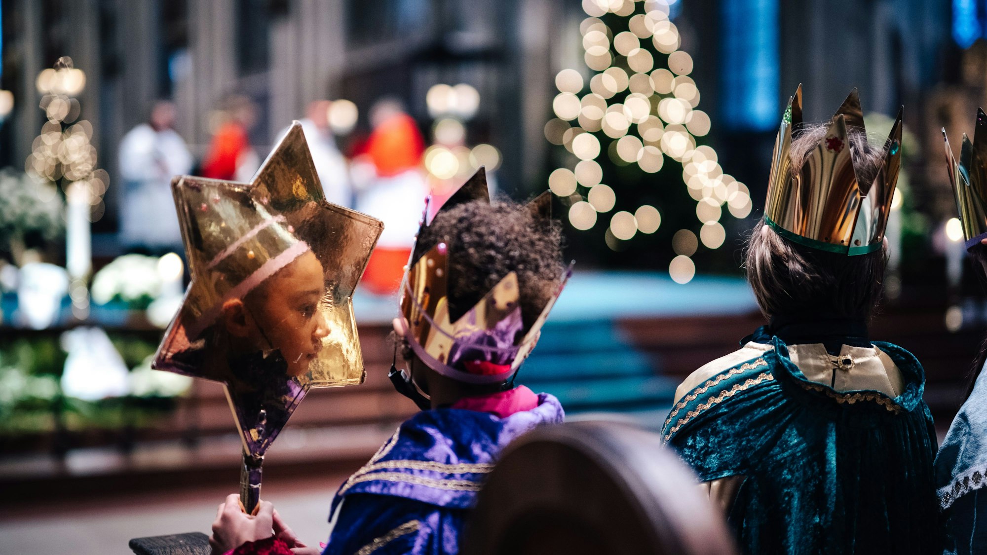 Glitzernde Gewände und ein feierlicher Augenblick: Sternsinger bei der Aussendungsfeier im Dom. In dem selbstgebastelten großen Stern eines der Kinder spiegelt sich sein Gesicht.