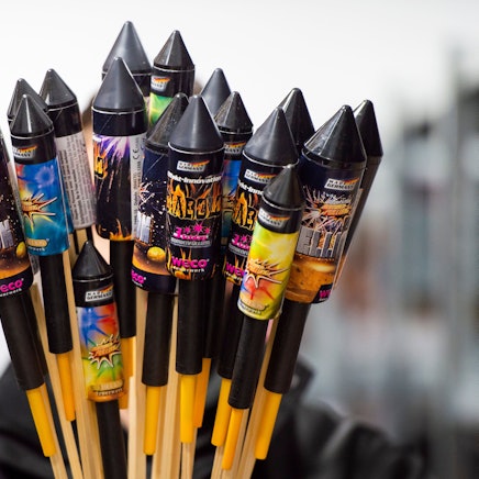 Jemand hält in einem Lagerraum Silvesterraketen.