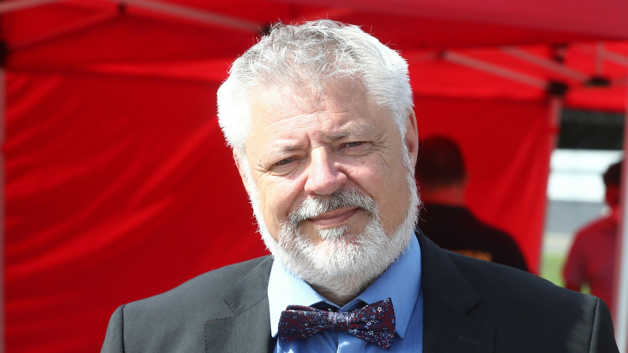 Prof. Dr. Alexander Michael Lechleuthner vor rotem Hintergrund.