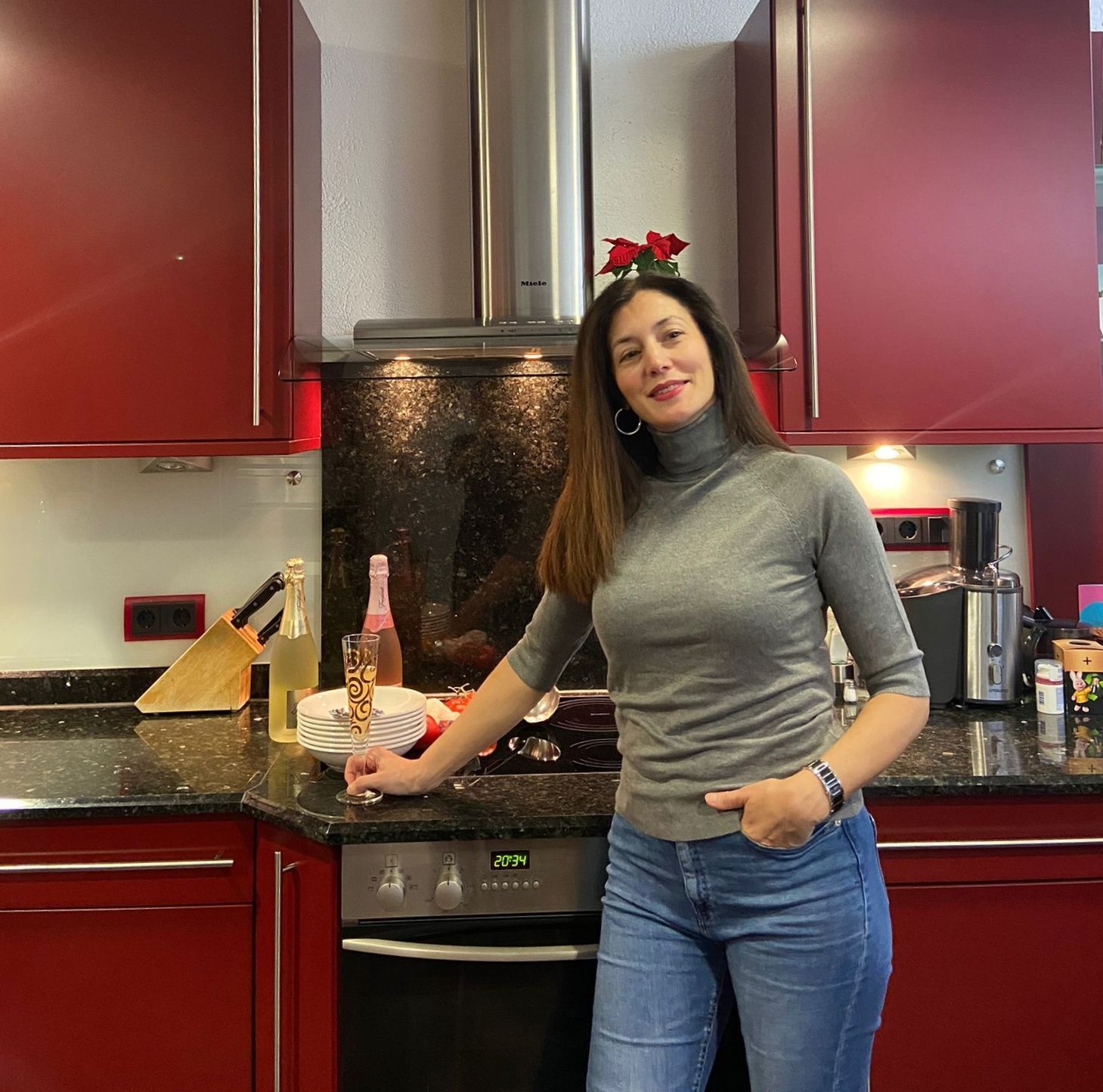 Eneka Krämer-Razquin  steht in ihrer Küche mit roten Schränken, ein Glas Sekt in der Hand.