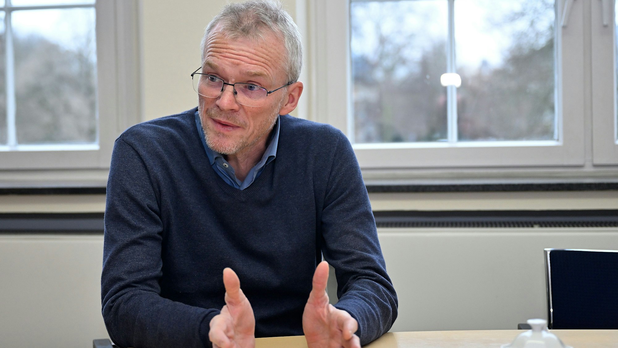 Bergisch Gladbachs Bürgermeister Frank Stein sitzt an einem Tisch und gestikuliert.