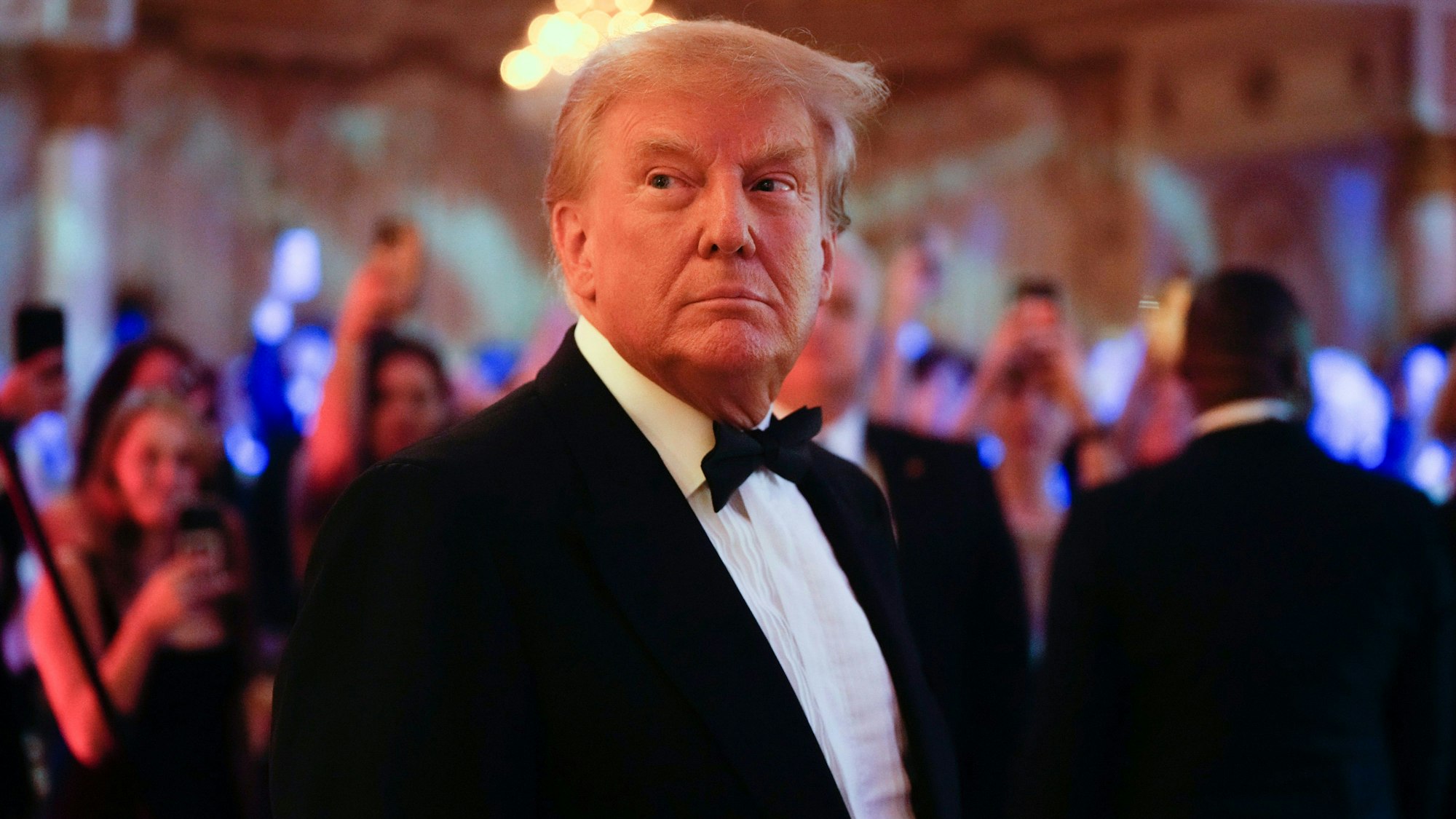 Der frühere US-Präsident Donald Trump steht in einem Anzug auf einer Party.