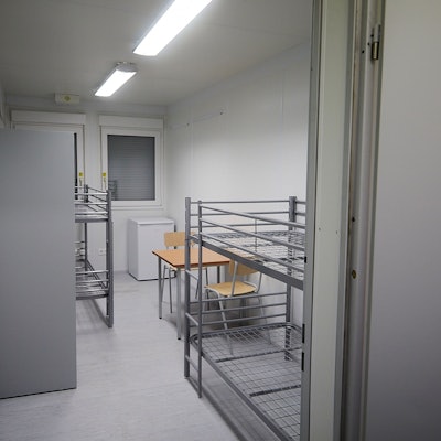 Ein Schlafraum mit zwei Etagenbetten, einem kleinen Tisch und zwei Stühlen.