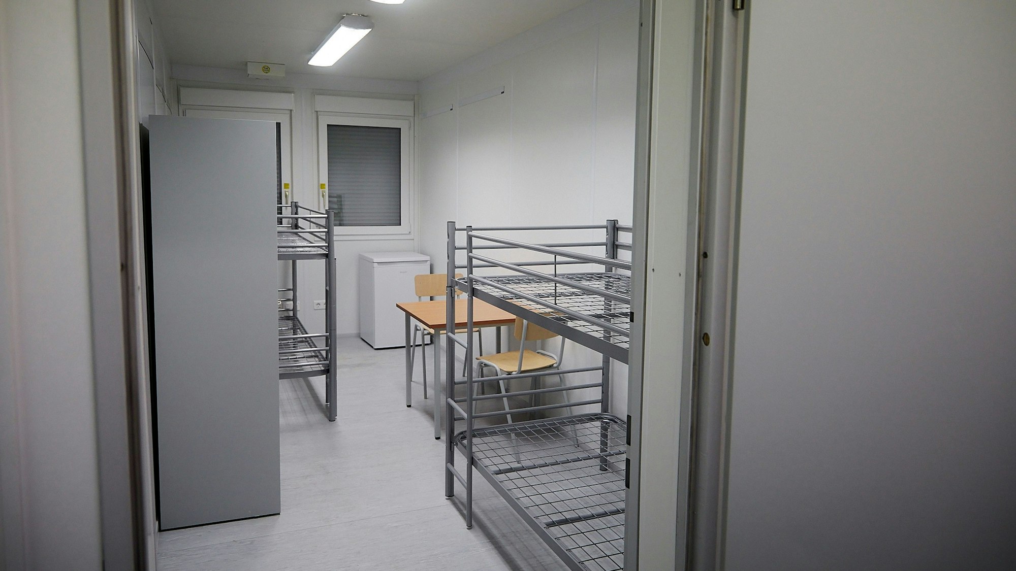 Ein Schlafraum mit zwei Etagenbetten, einem kleinen Tisch und zwei Stühlen.