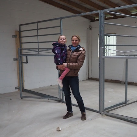 Das Bild zeigt Anne Spoo mit Tochter Paulina vor den Pferdeboxen.