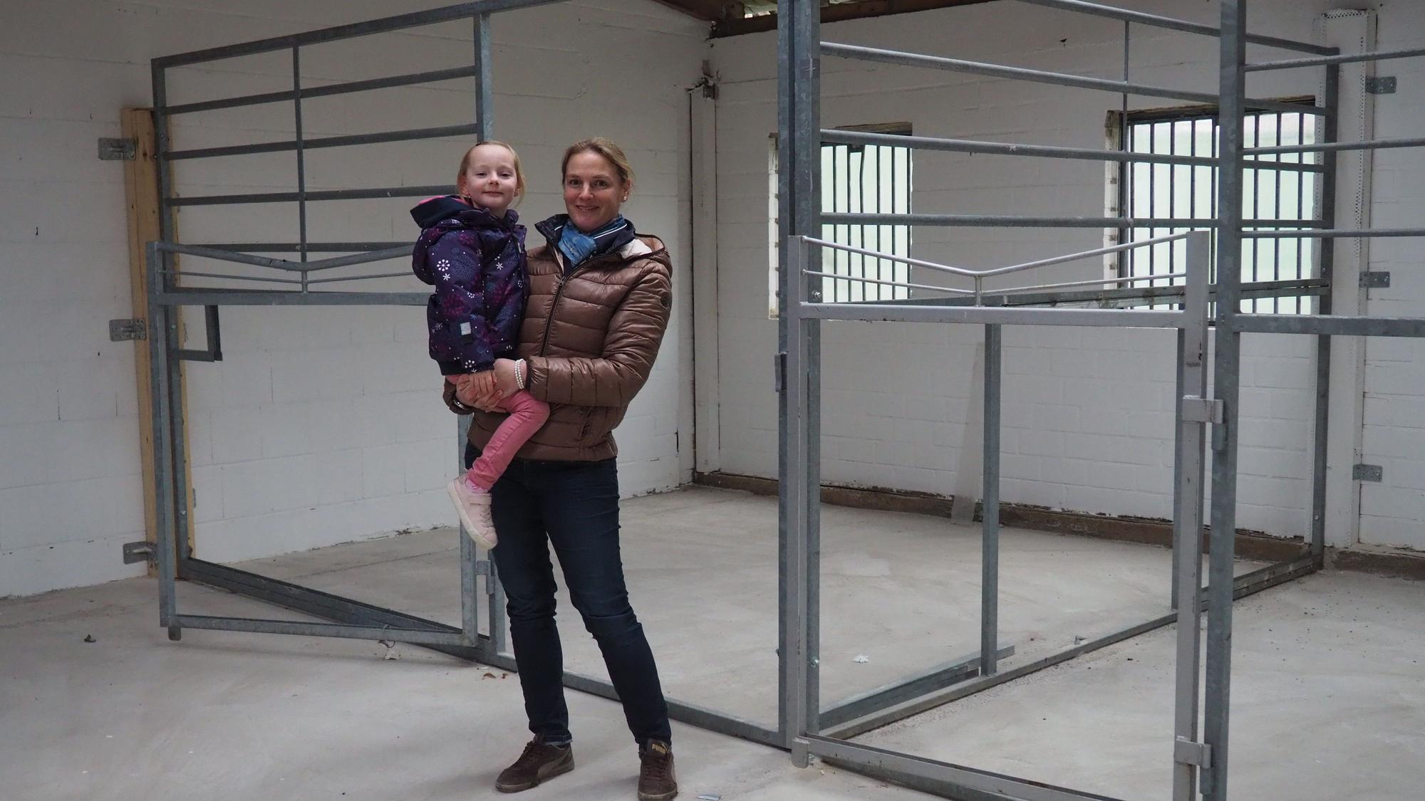 Das Bild zeigt Anne Spoo mit Tochter Paulina vor den Pferdeboxen.