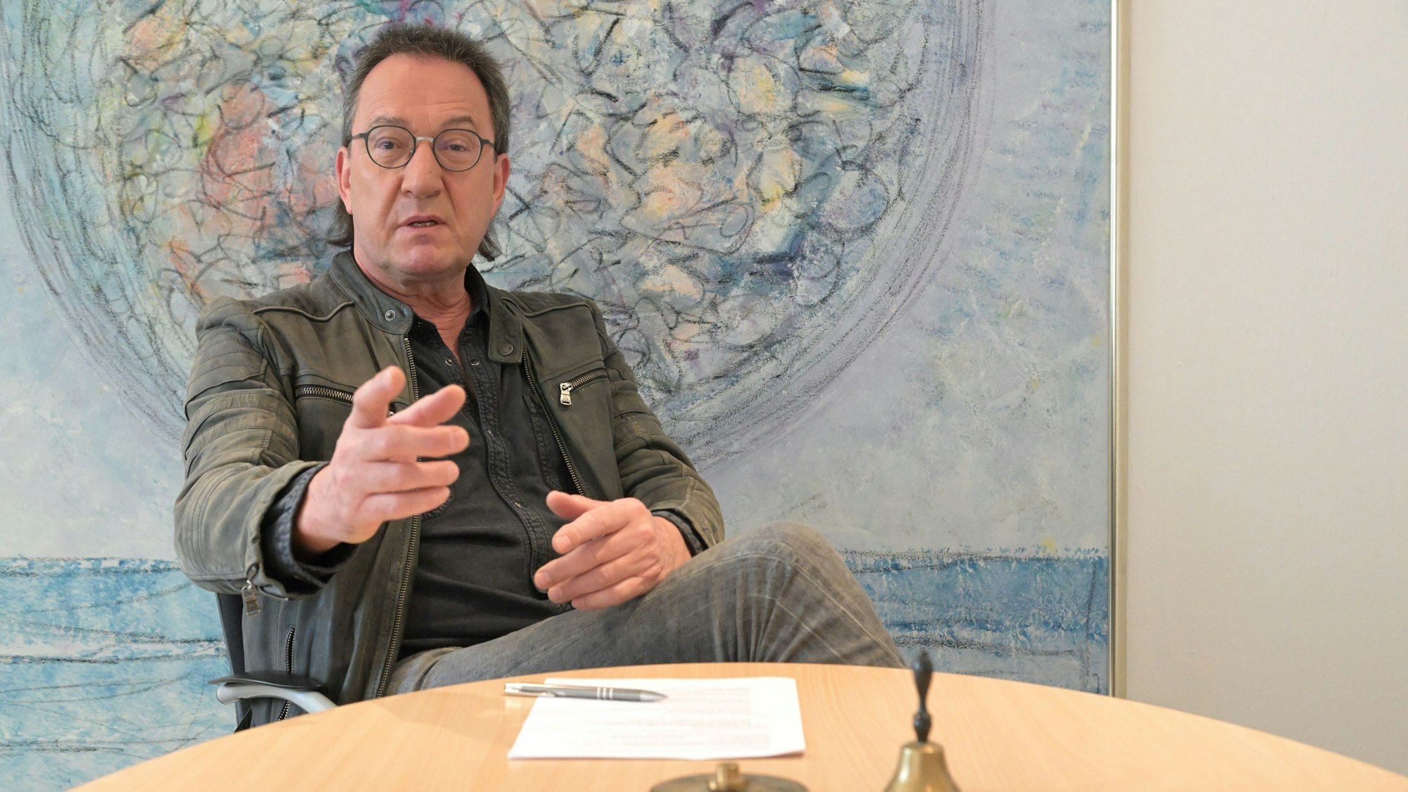 Bernd Sassenhof sitzt an einem Tisch und gestikuliert.
