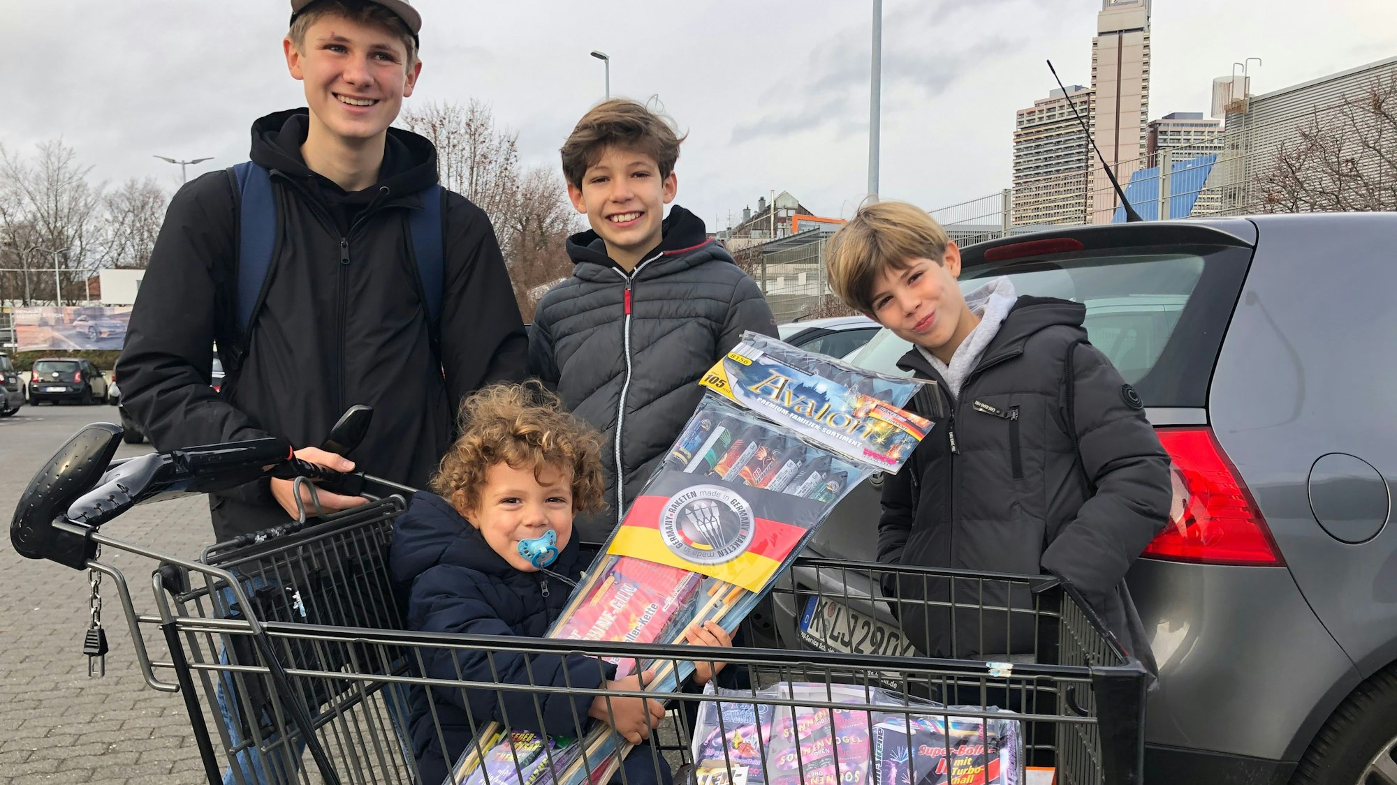 „Sehr!“ freuen sich José, Jonathan und Mike (Namen geändert) auf Silvester. Schwesterchen Lily ist jetzt schon happy. Sie sitzt in dem Einkaufswagen und hält strahlend eine Packung Leuchtraketen in der Hand. Ihre drei Brüder stehen dahinter und lächeln cool.