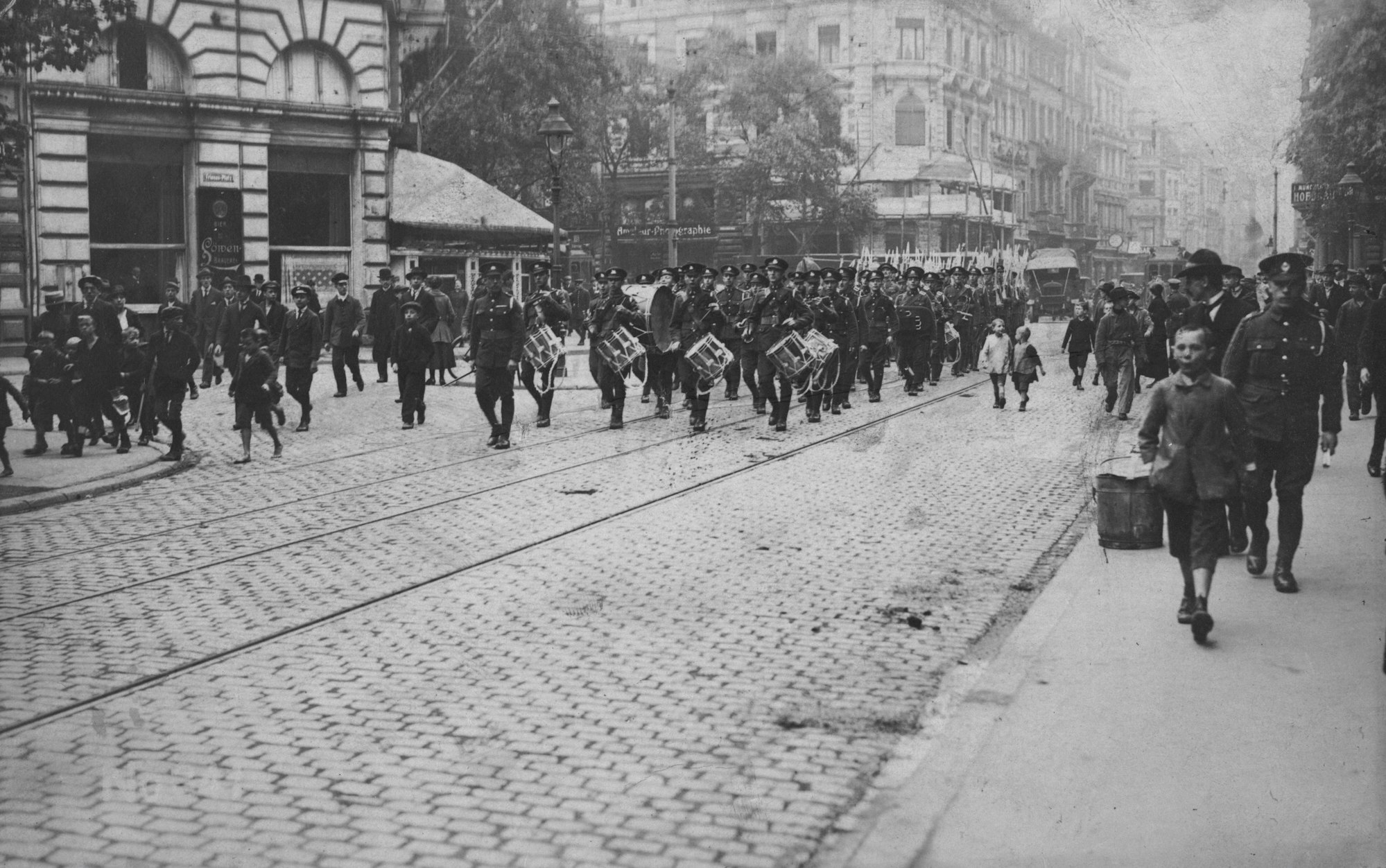 Die Aufnahme zeigt Männer in Uniform, die mit Trommeln durch die Kölner Innenstadt ziehen.