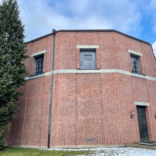 Ein nahezu runder Fachwerkbau mit dunkler Tür und Fenstern nur im oberen Bereich steht in winterlicher Landschaft.