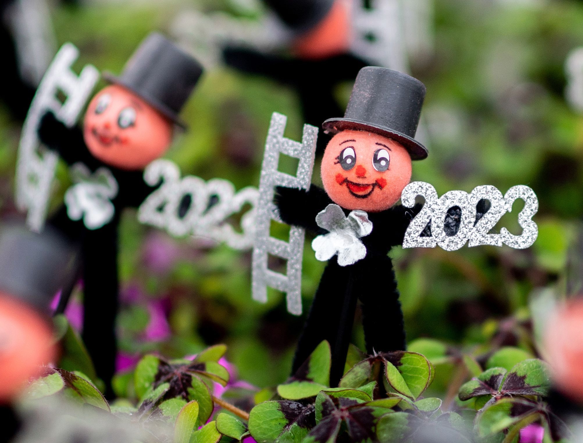 Zwei Glücksklee halten eine Treppe und "2023" in der Hand
