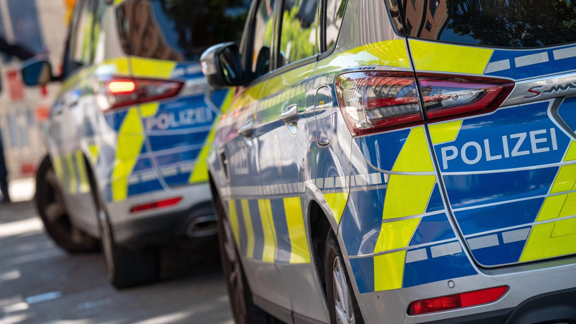 Zwei Polizeifahrzeuge stehen hintereinander an einer Straße.