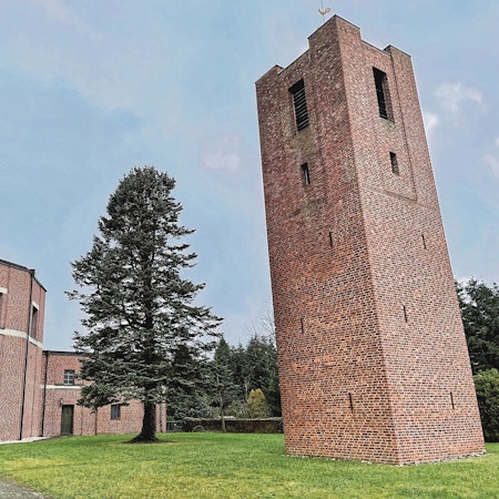 Rechts steht ein hoher, viereckiger Backsteinturm, links ein Rundbau ebenfalls aus Backsteinen. Das Gebäudeensemble liegt in einem kleinen Park, in dem ein hoher Nadelbaum steht.
