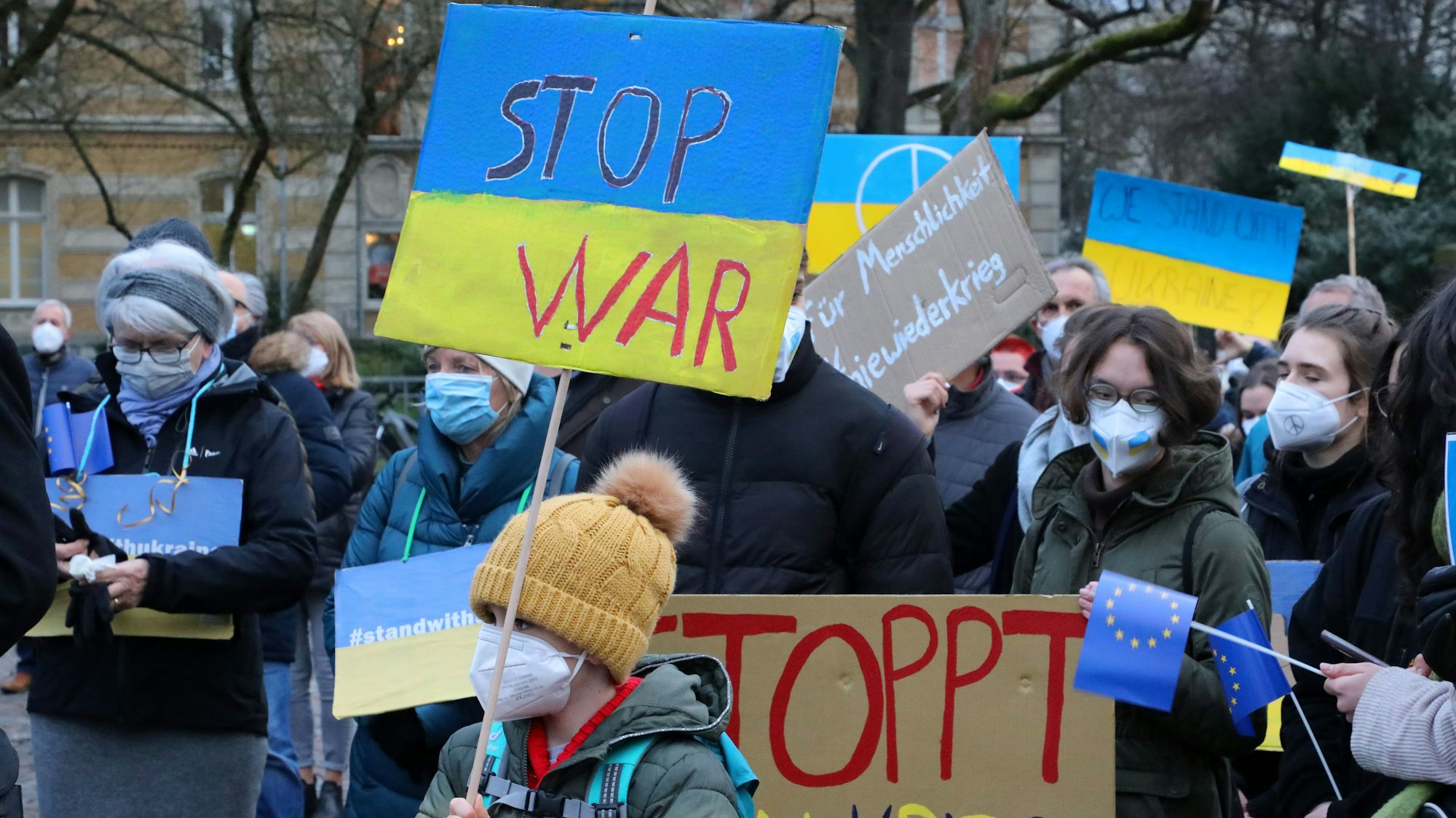 Teilnerhmer einer Demo mit blau-gelben Schildern und Transparenten.