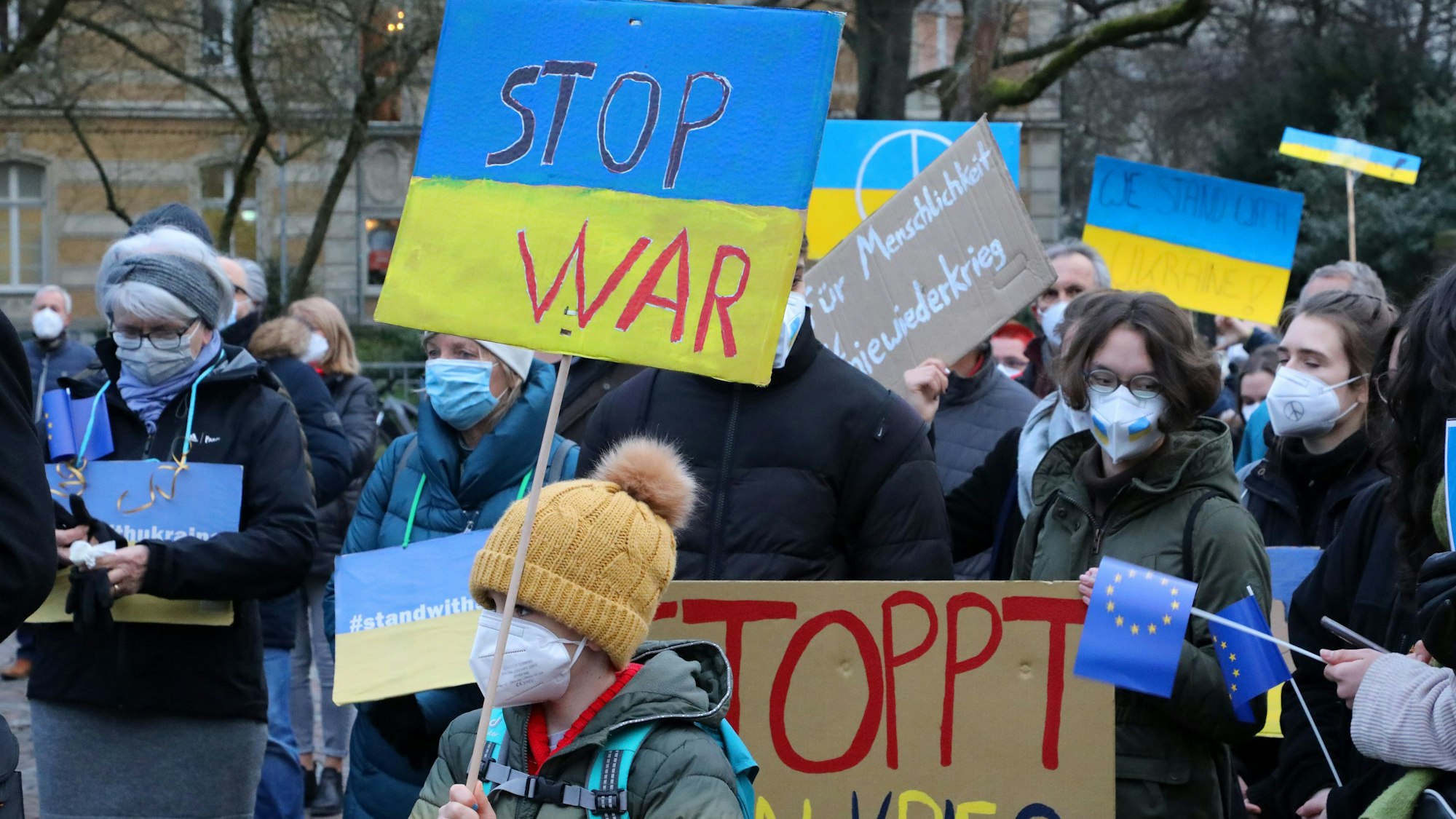 Menschen protestieren mit Plakaten auf dem Bergisch Gladbacher Konrad-Adenauer-Platz gegen den russischen Angriffskrieg auf die Ukraine.