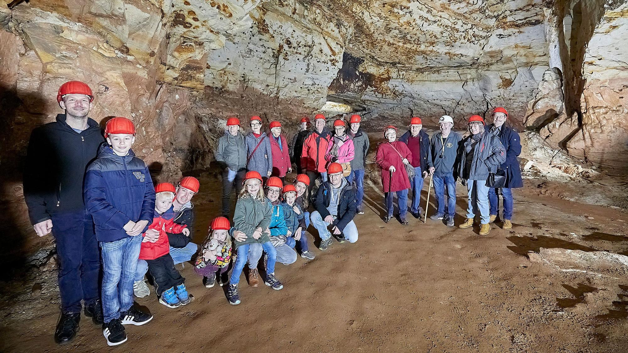 Eine Besuchergruppe ist mit roten Helmen ausgestattet im Besucherbergwerk unterwegs.