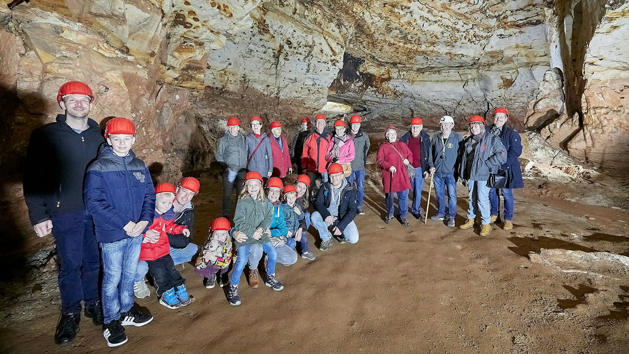 Eine Besuchergruppe ist mit roten Helmen ausgestattet im Besucherbergwerk unterwegs.