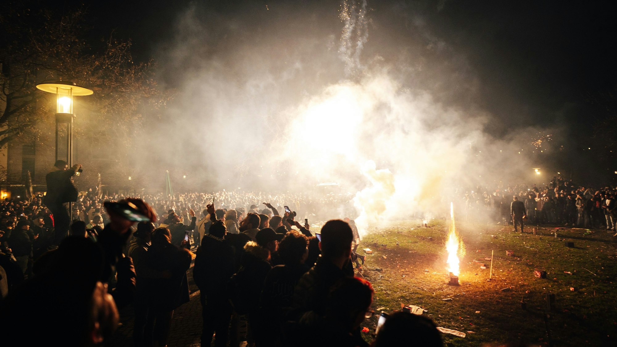 Qualm steig im Nachthimmel zwischen Menschen und Feuerwerk auf.