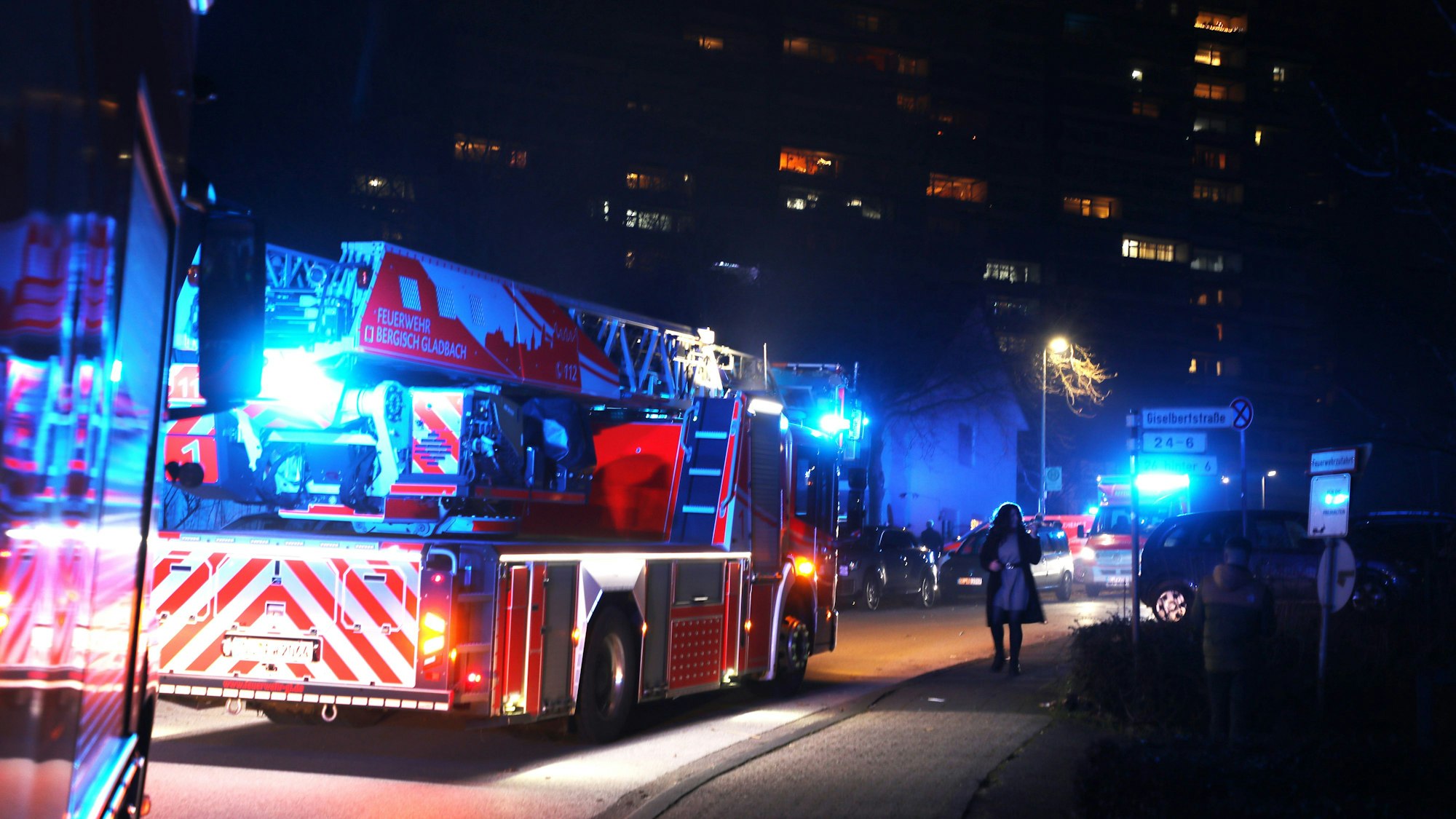 Ein Löschwagen steht im Vordergrund. Im Hintergrund sieht man Lichter in den Wohnhäusern.