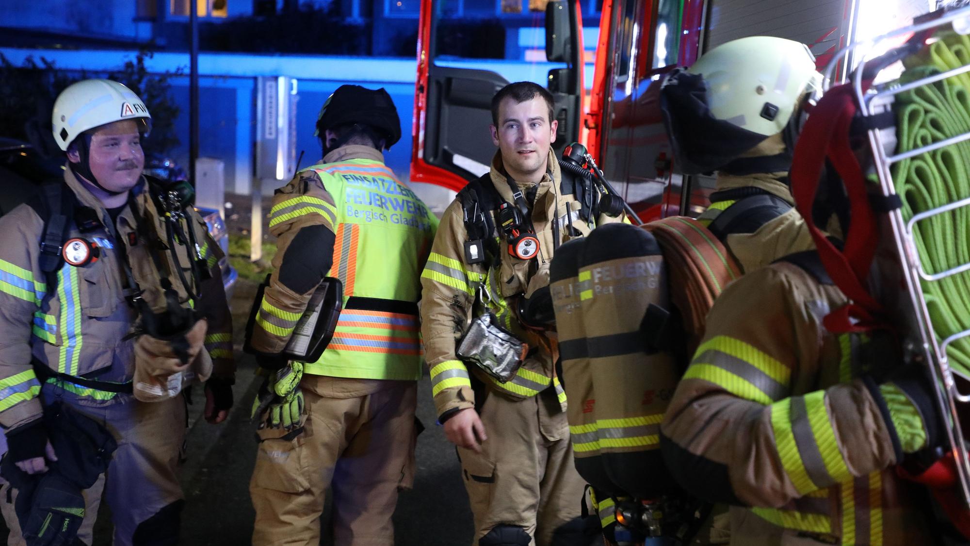 Feuerwehrleute gehen zu einem Einsatzfahrzeug, in das ein Feuerwehrmann Ausrüstung einlädt.