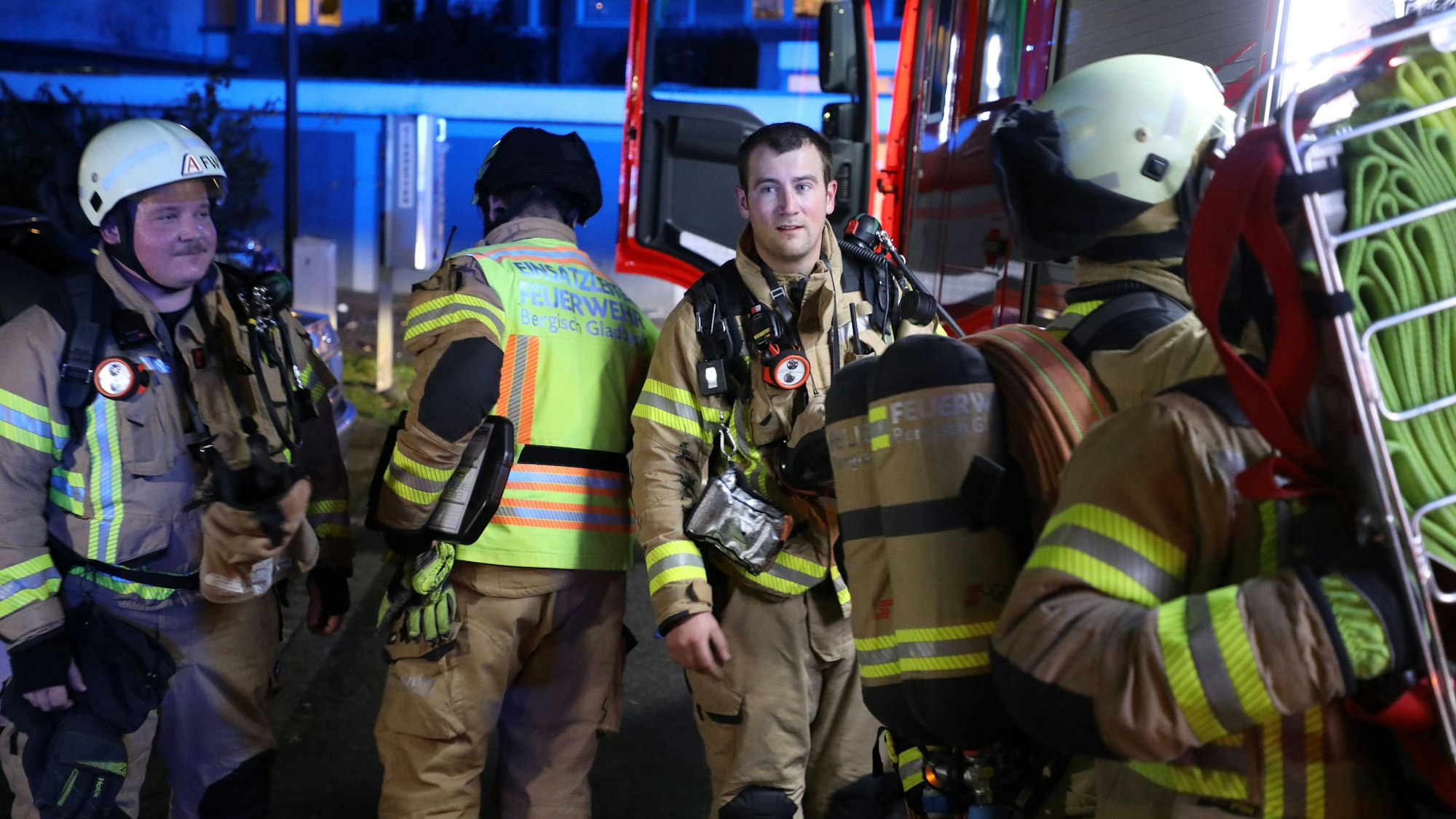 Feuerwehrleute gehen zu einem Einsatzfahrzeug, in das ein Feuerwehrmann Ausrüstung einlädt.