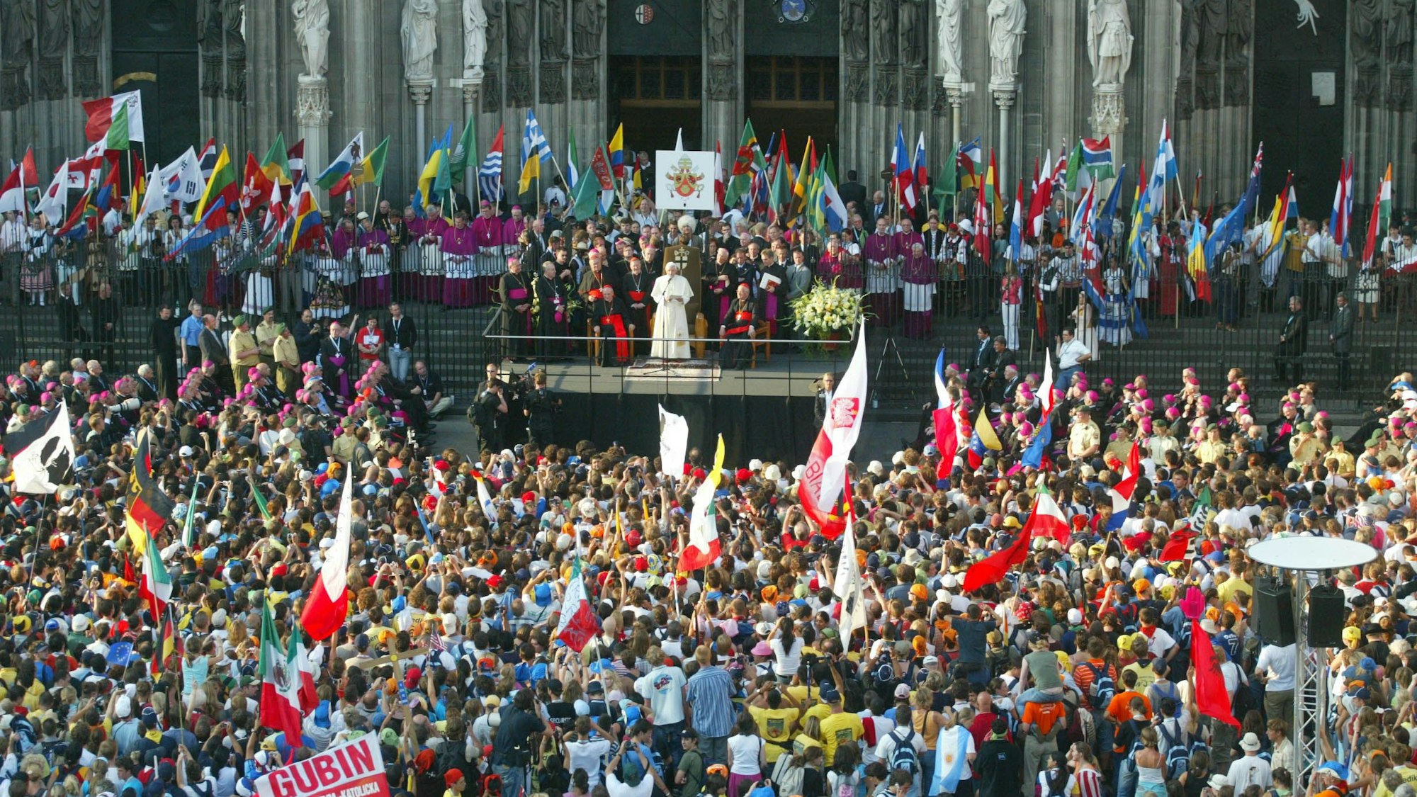 Gläubige stehen beim Weltjugendtag 2005 vor dem Dom und hören dem Papt zu.