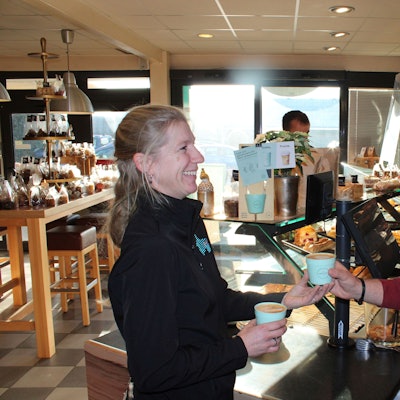 Zwei Mitarbeiter im Laden mit Recup Mehrwegbechern in der Hand.