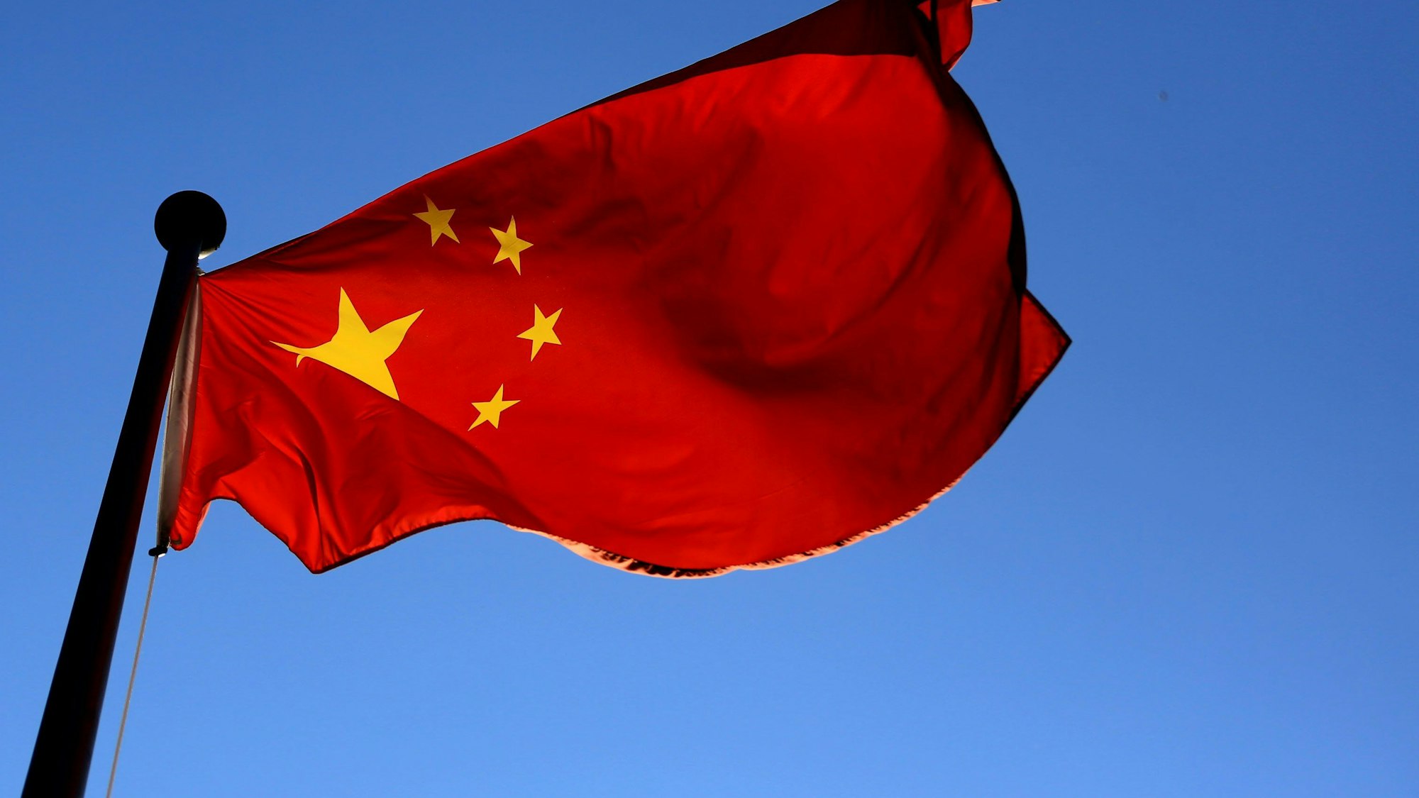 Die Fahne Chinas weht vor einem strahlend blauen Himmel.