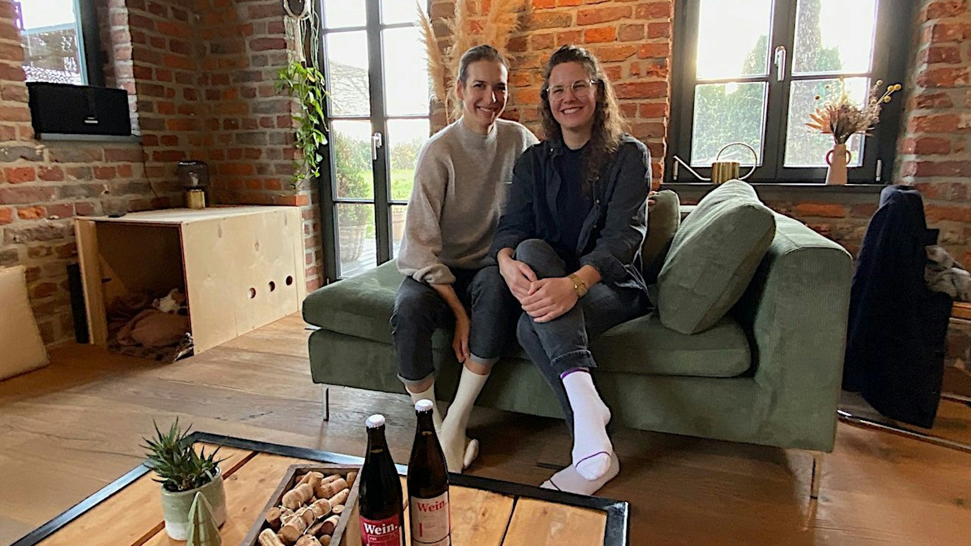 Leonie Berents und Silja Mende-Kamps (rechts) sitzen auf einer Couch.