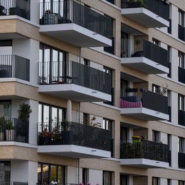 Zu sehen sind mehrere neu gebaute Wohnhäuser, deren Balkone dicht aneinander liegen.
