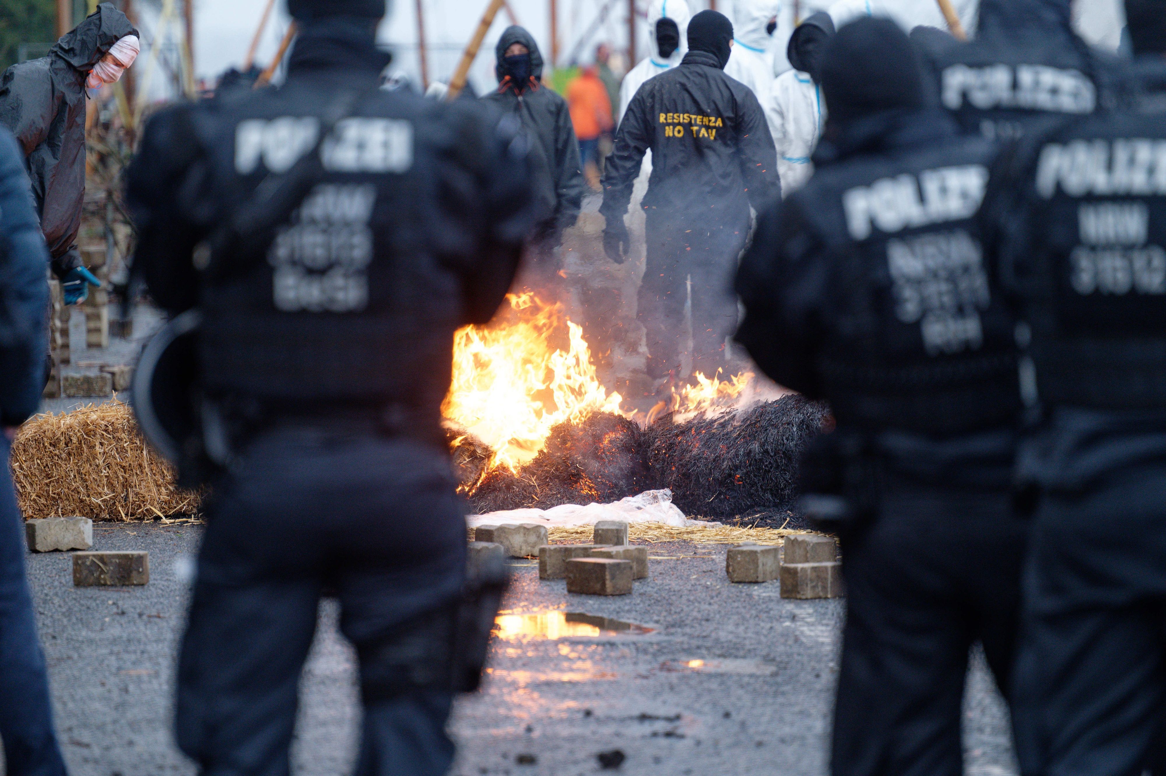 Polizisten und Klimaschützer stehen sich in Lützerath an einer brennenden Barrikade gegenüber.