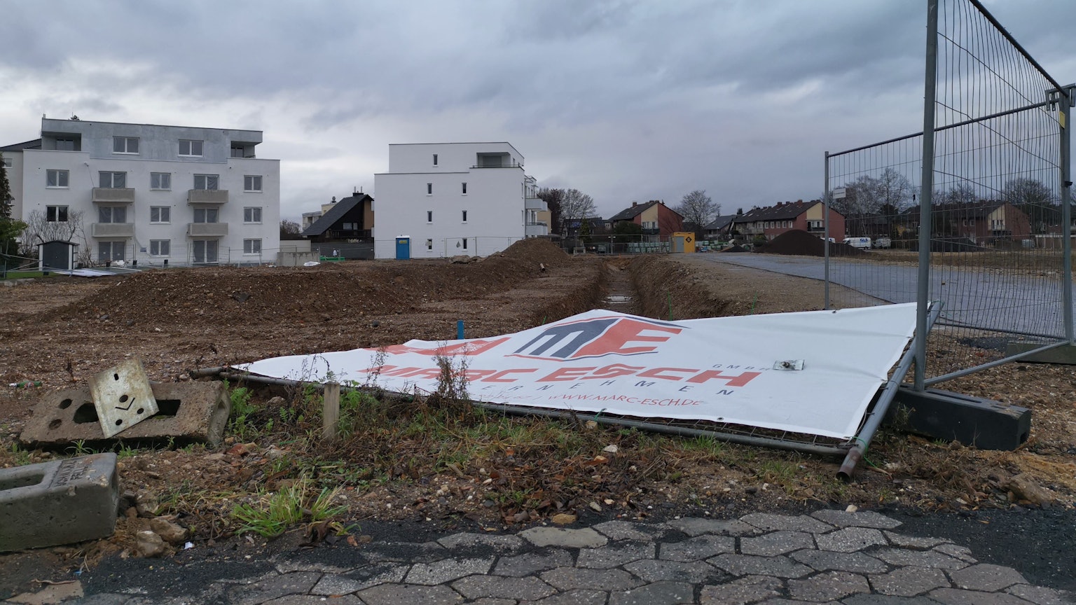Wohnungsbau in Rheinbach: Ein Bauschild liegt umgestürzt auf einer Brachfläche.