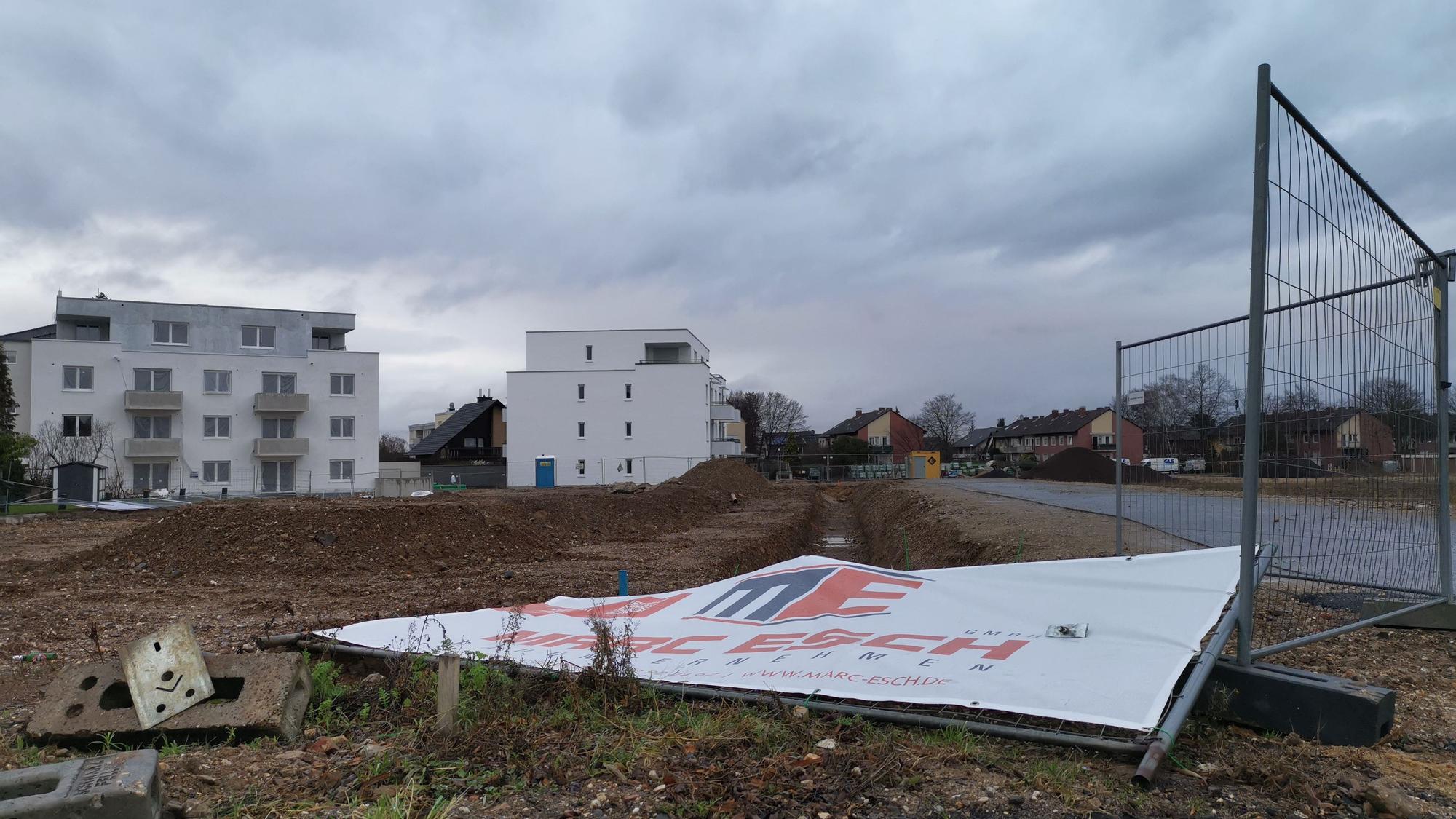 Wohnungsbau in Rheinbach: Ein Bauschild liegt umgestürzt auf einer Brachfläche.