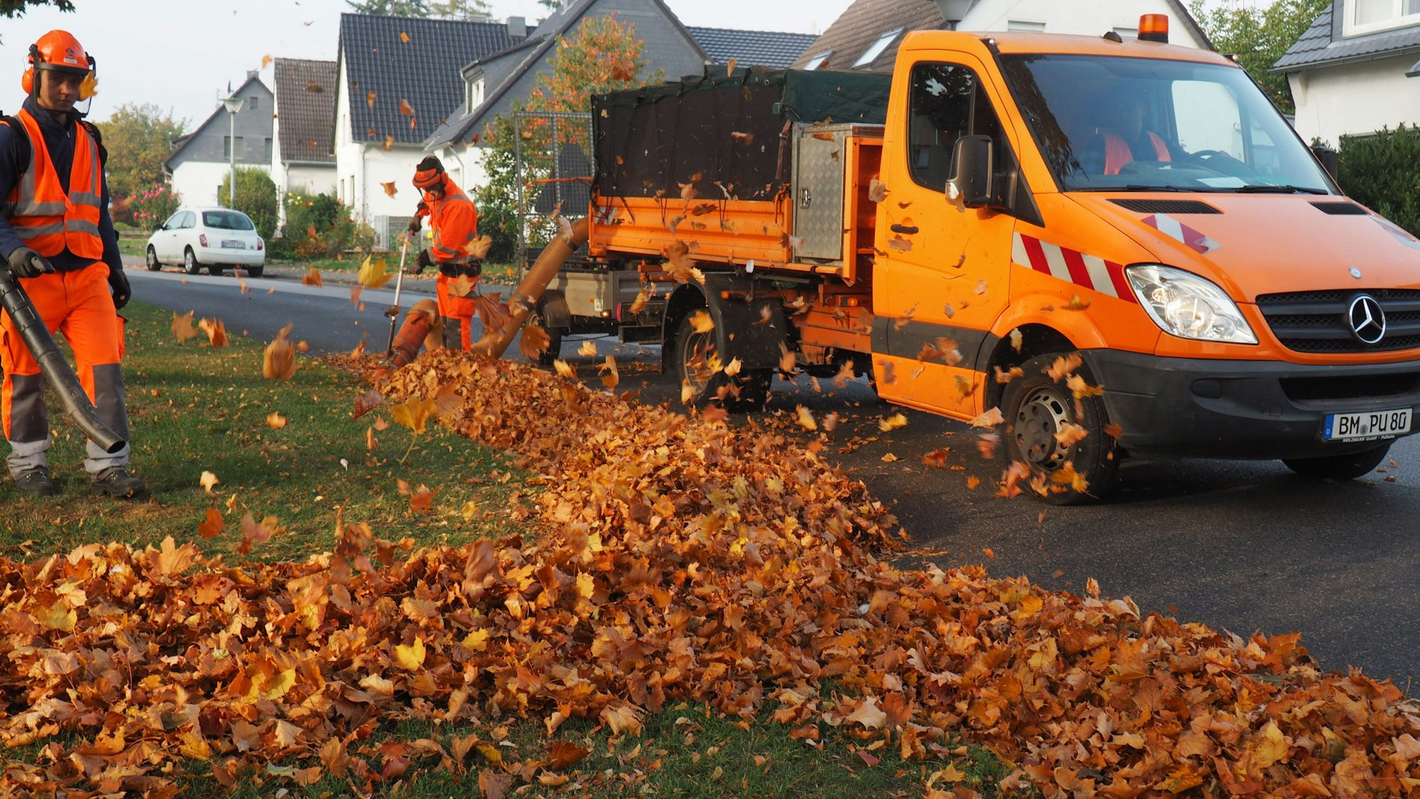 Zwei städtische Mitarbeiter räumen Laub im Herbst.